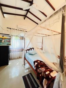 a bedroom with a bed with a mosquito net at Villa Kethmin in Talpe