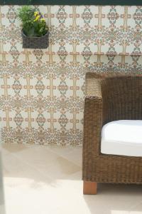 a wicker chair in front of a wall with wallpaper at Cantinho da Celeste in Paramos +2 photos