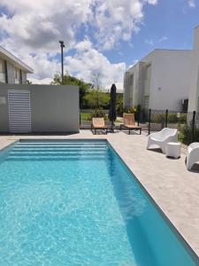 een zwembad met 2 stoelen en een gebouw bij Cosy T2 clim - Piscine - À 5 min des plages de Saint-François in Saint-François