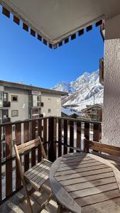 een houten terras met een tafel en een bank op een balkon bij Trilocale centro Cervinia in Breuil-Cervinia