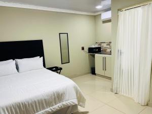a bedroom with a white bed and a kitchen at PholaBnB in Pongola