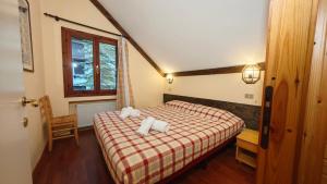 - une chambre dotée d'un lit avec une couverture rouge et blanche dans l'établissement Hostdomus- Abeti Apartments, à Sestrières