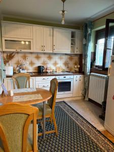 a kitchen with white cabinets and a table with chairs at Apartman 23 in Kraljevo