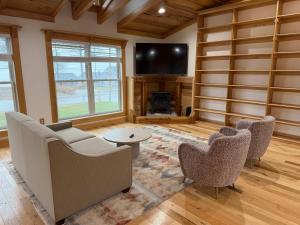 een woonkamer met een bank en stoelen en een flatscreen-tv bij Lake Rd E- Geneva in Saybrook-on-the-lake