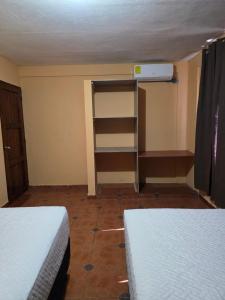 een kamer met 2 bedden en een boekenplank bij Hotel y Restaurante Punta Corona in Acajutla +4 foto's
