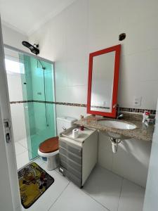 a bathroom with a toilet and a sink and a mirror at Casa Silva enseada in Guarujá