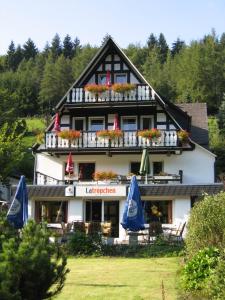 un grand bâtiment avec des parasols en face de celui-ci dans l'établissement Pension & Ferienhaus Latröpchen, à Schmallenberg