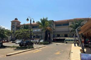 a large building with cars parked in a parking lot at Sunset Statehouse View Residence B in Entebbe