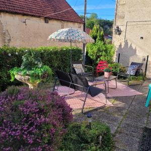 eine Terrasse mit Stühlen, einem Sonnenschirm und Blumen in der Unterkunft Maison de charme 175m2 - 5 chambres in Aignay-le-Duc