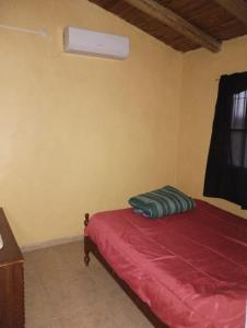 Schlafzimmer mit einem Bett mit roter Bettwäsche und einem Fenster in der Unterkunft CABAÑA NUESTRO HOGAR in San Rafael