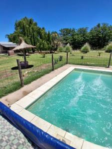 ein Pool in einem Garten mit einem Zaun in der Unterkunft CABAÑA NUESTRO HOGAR in San Rafael