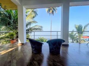 deux chaises dans une pièce avec vue sur des palmiers dans l'établissement GS Home on the Bay - Super Sea view glass studio apartment, à Vagator
