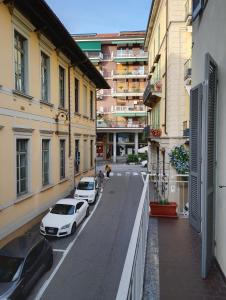 Twee witte auto's geparkeerd op een straat tussen gebouwen. bij Appartamento di Marilù in Verbania