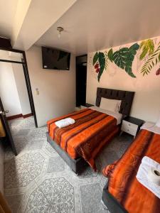 ein Schlafzimmer mit zwei Betten und einem Flachbildfernseher in der Unterkunft Hostal Mónaco in Machu Picchu