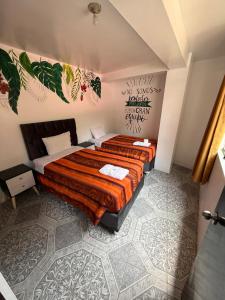 ein Schlafzimmer mit einem großen Bett mit orangefarbener Bettwäsche in der Unterkunft Hostal Mónaco in Machu Picchu