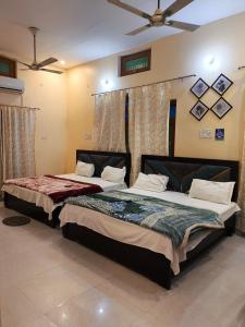 twee bedden in een kamer met bij OM Palace Guest House-Fully Air Conditioned in Ayodhya