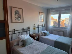 een hotelkamer met twee bedden en een raam bij A CALZADA in Cambados