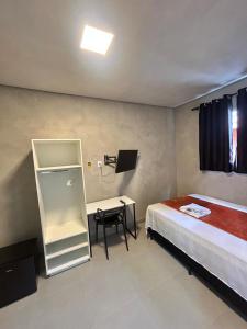 a bedroom with a bed and a desk and a chair at #108 Suíte Acolhedora com vaga Centro de Itatiba in Itatiba