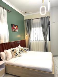 een slaapkamer met een groot wit bed voor een raam bij Sunset Statehouse View Residence in Entebbe