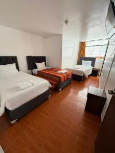 ein Hotelzimmer mit zwei Betten und einem Fenster in der Unterkunft Hostal Mónaco in Machu Picchu