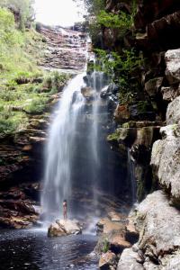 a person standing in the water in front of a waterfall at Casa Kahlo in Lençóis