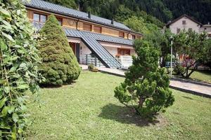 een tuin met twee bomen voor een gebouw bij Casa Per Ferie Arta Terme in Arta Terme