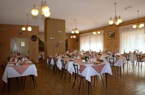 een grote kamer met tafels en stoelen met witte tafelkleden bij Casa Per Ferie Arta Terme in Arta Terme