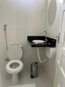 a bathroom with a white toilet and a sink at Suíte privativa in Boa Vista
