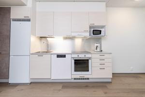 una cucina con mobili bianchi e un forno a microonde di Cozy apartment for three by the ski trails a Sotkamo