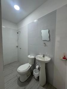 a white bathroom with a toilet and a sink at Hotel Casa Colonial Moñitos in Moñitos