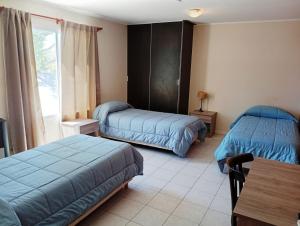 una camera da letto con due letti, un tavolo e una finestra di El Portal Hoteles y Aparts a Rincon de los Sauces Altre 10 foto