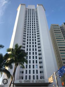 a tall white building with a palm tree in front of it at Torres Gemelas Costera MA con Playa Privada in Acapulco