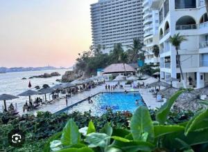 a resort with a swimming pool next to the ocean at Torres Gemelas Costera MA con Playa Privada in Acapulco