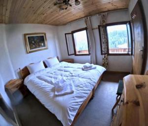 een slaapkamer met een groot bed met witte lakens bij Rium Dolomiti - Casa con Vista in Pieve di Cadore