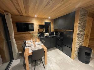 una cucina con un tavolo, un fornello e un frigorifero di Les 2 Chalets Alpins a Saint-Michel-de-Chaillol Altre 11 foto