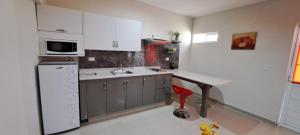 a kitchen with white cabinets and a table in it at Tres Palmas Departamentos in Los Mochis