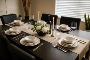 ein Esstisch mit Tellern und Weingläsern in der Unterkunft Crew Stay Sleeps 16 Work, Cook, Play & Relax in Navo