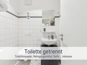 een wit betegelde badkamer met een wastafel en een spiegel bij Albert & Viktoria Loft mit Parkplätzen in Coburg +15 foto's