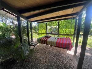 een overdekte veranda met een bed en een stoel bij Cabañita tipo Chalet in Fortuna