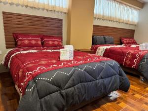 twee bedden in een kamer met rood en zwart bij Gran Hotel Real in Huancayo