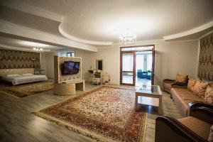 a living room with a couch and a tv at Park EmpAir Hotel in Pavlodar