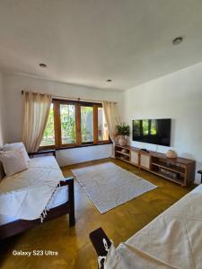 een woonkamer met 2 bedden en een flatscreen-tv bij Casa Uzêda Trancoso in Porto Seguro
