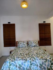 a bed in a bedroom with two windows and a light at Casa Miava - Studio 1 in Marau