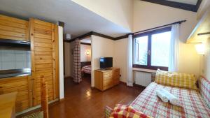 Cette chambre comprend un lit, une télévision et une fenêtre. dans l'établissement Hostdomus- Abeti Apartments, à Sestrières