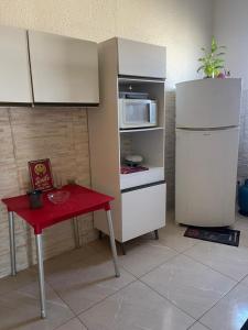 a small kitchen with a red table and a refrigerator at Hostel Mariah in Cabo Frio