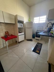 a kitchen with white appliances and a red table at Hostel Mariah in Cabo Frio
