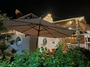 un ombrello di notte davanti a una casa di มินิฮาร์ท เฮาส์บีช Mini Heart House Beach a Ban Chak Phai
