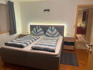 a bed with blue and white pillows on it at Landhaus Ganzer in Niedernsill
