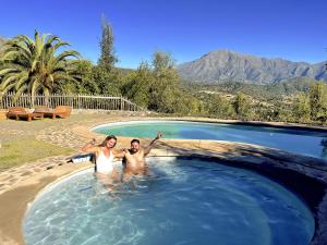 a man and a woman standing in a swimming pool at Swiss Eco Lodge La Linda Loma - Olmué in Olmué