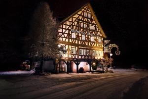 een verlicht gebouw in de sneeuw 's nachts bij Gasthof Waldgericht in Dornstetten